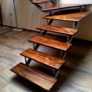 Escalera flotante con huellas de madera y barandal de cristal en casa de Andares.