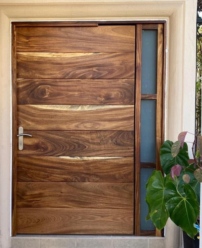 Puerta principal de madera sólida con diseño contemporáneo en residencia de Puerta de Hierro, Zapopan.