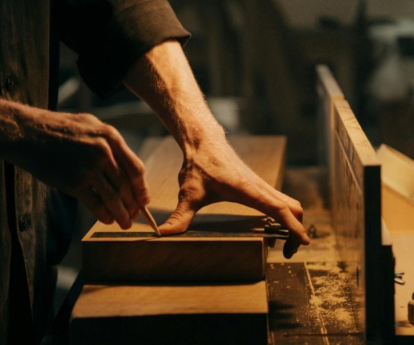 A craftsman skillfully sanding a wooden plank in a well-lit workshop.